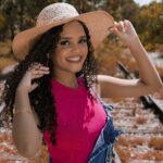 Cheerful woman in a straw hat and pink blouse smiling on railway tracks in Belo Horizonte, Brazil.
